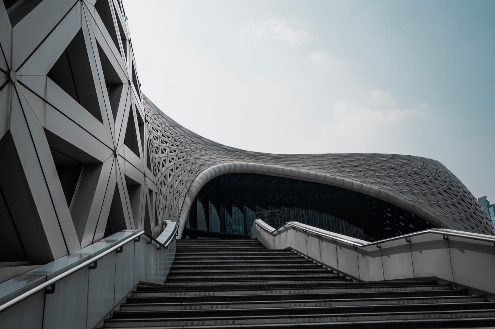 Modern building with a curved lattice facade above a wide staircase