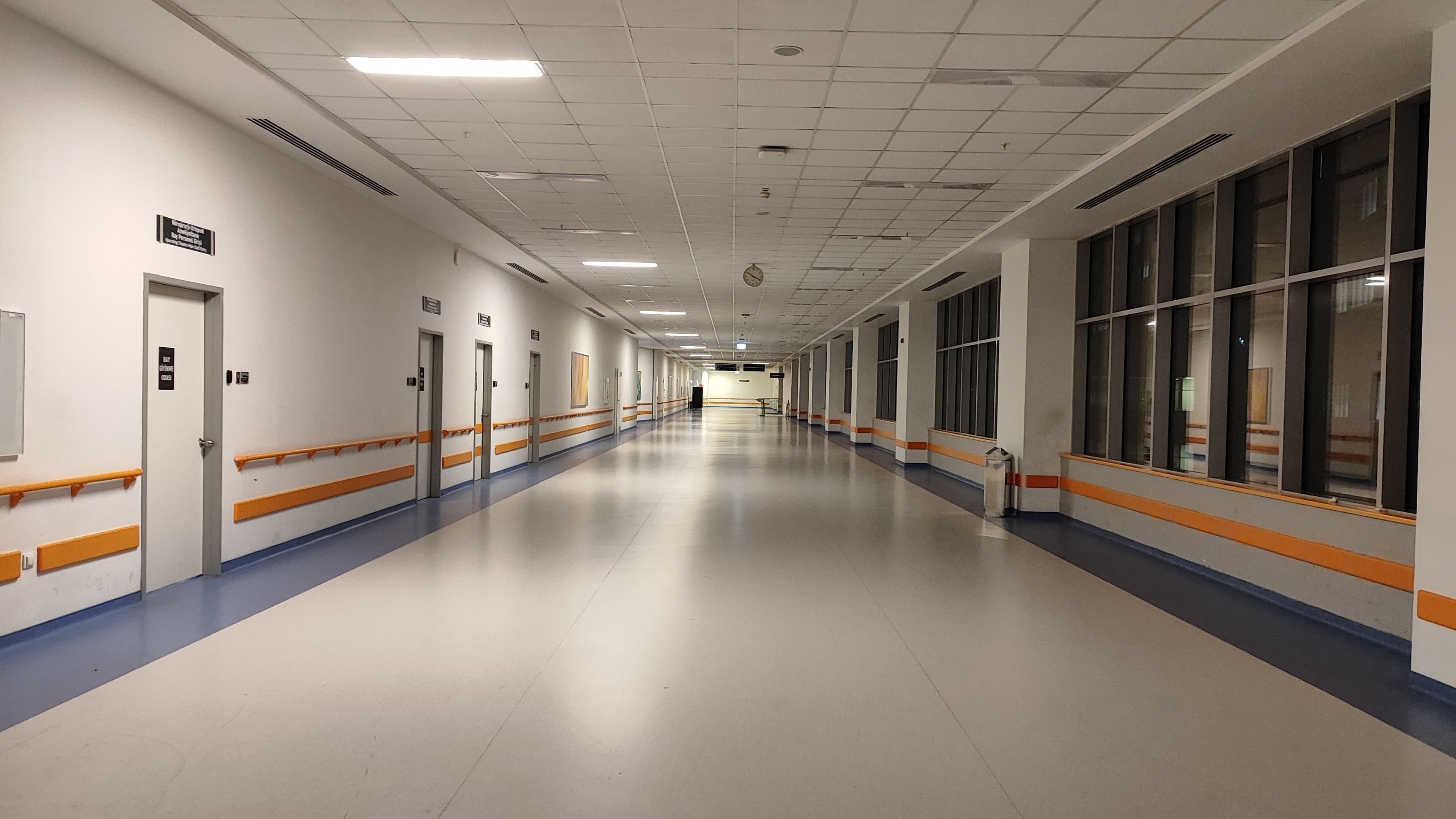 Empty hospital corridor with handrails and patient room doors