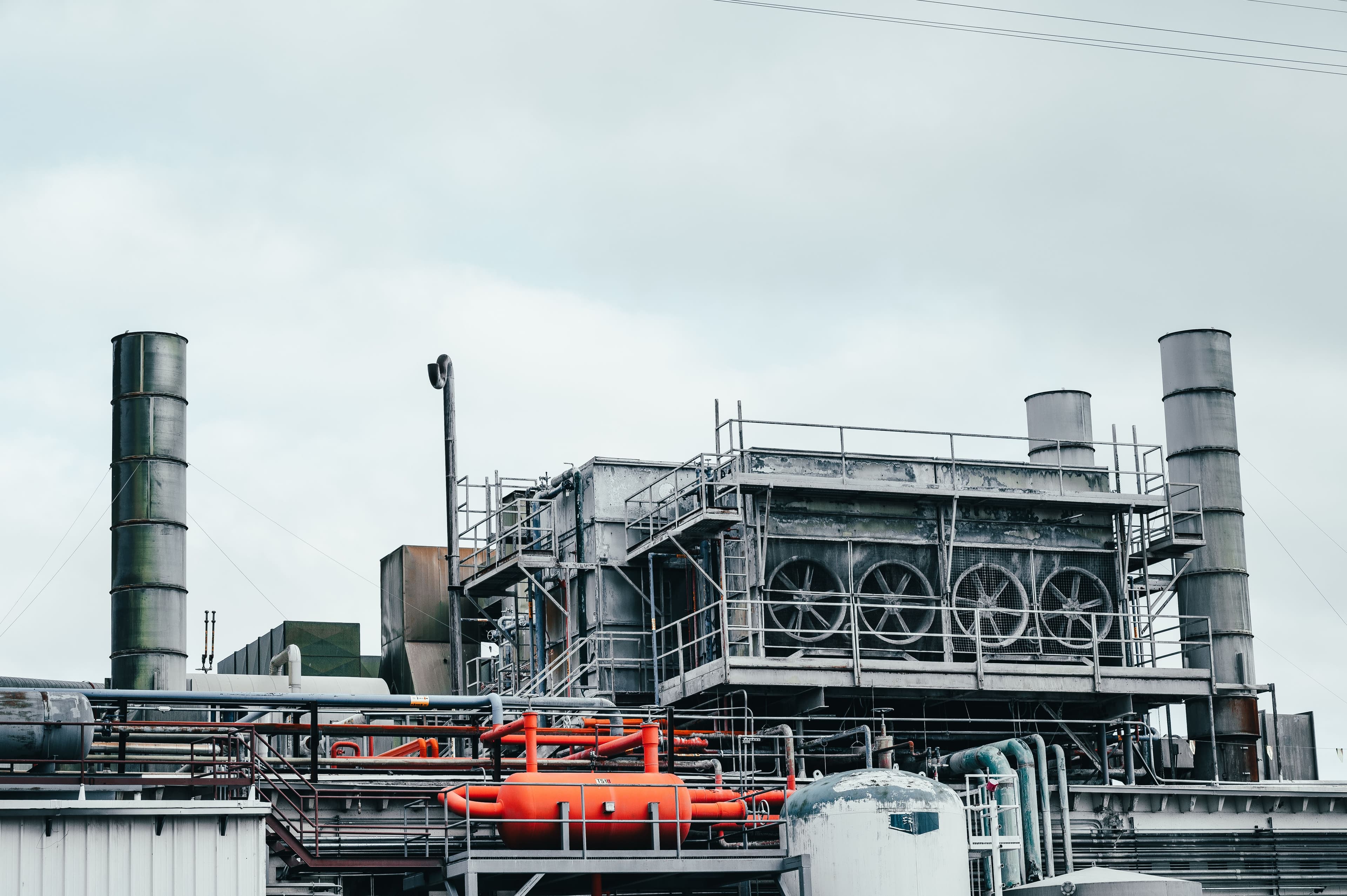 Industrial plant exterior with exhaust stacks, cooling fans and piping
