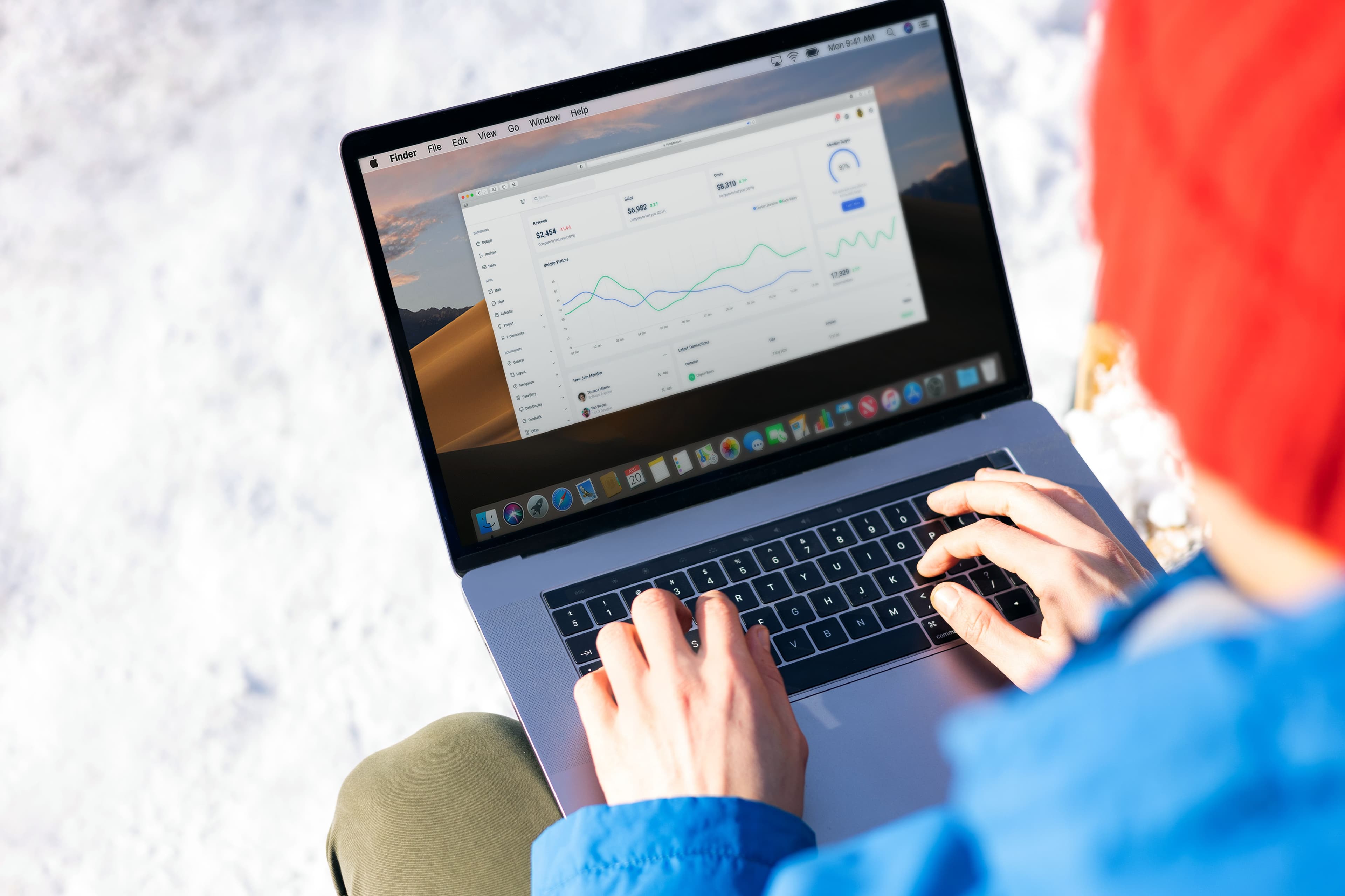 Person typing on a laptop displaying a data dashboard with charts and KPI figures