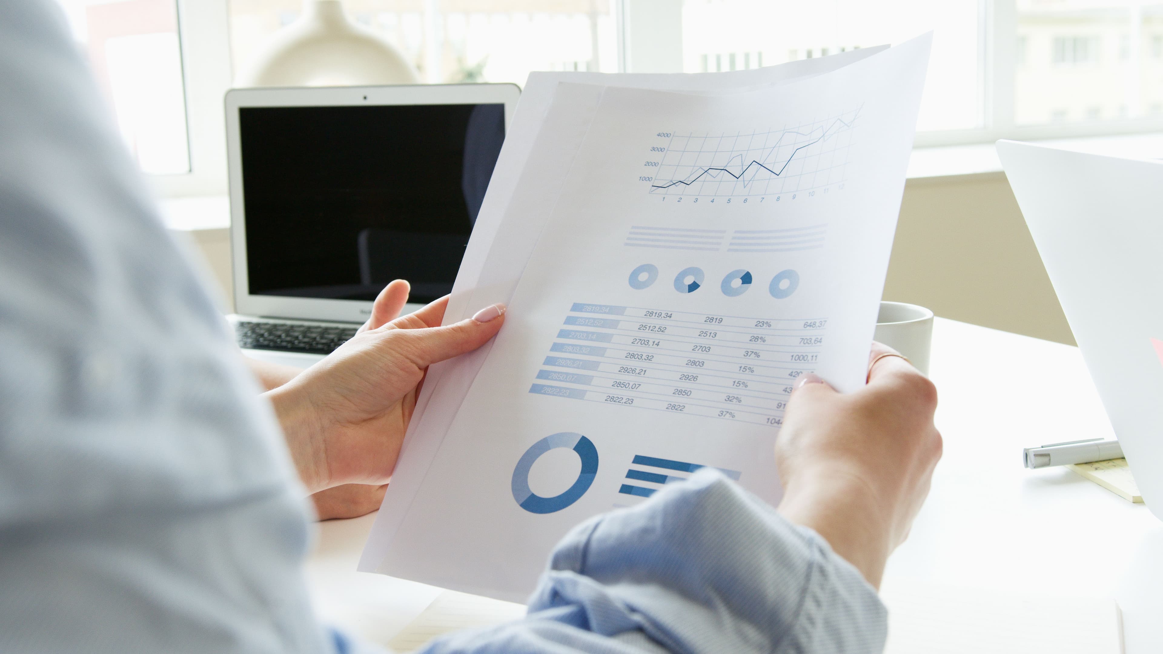 Person reviewing a printed report with charts and data tables at a desk