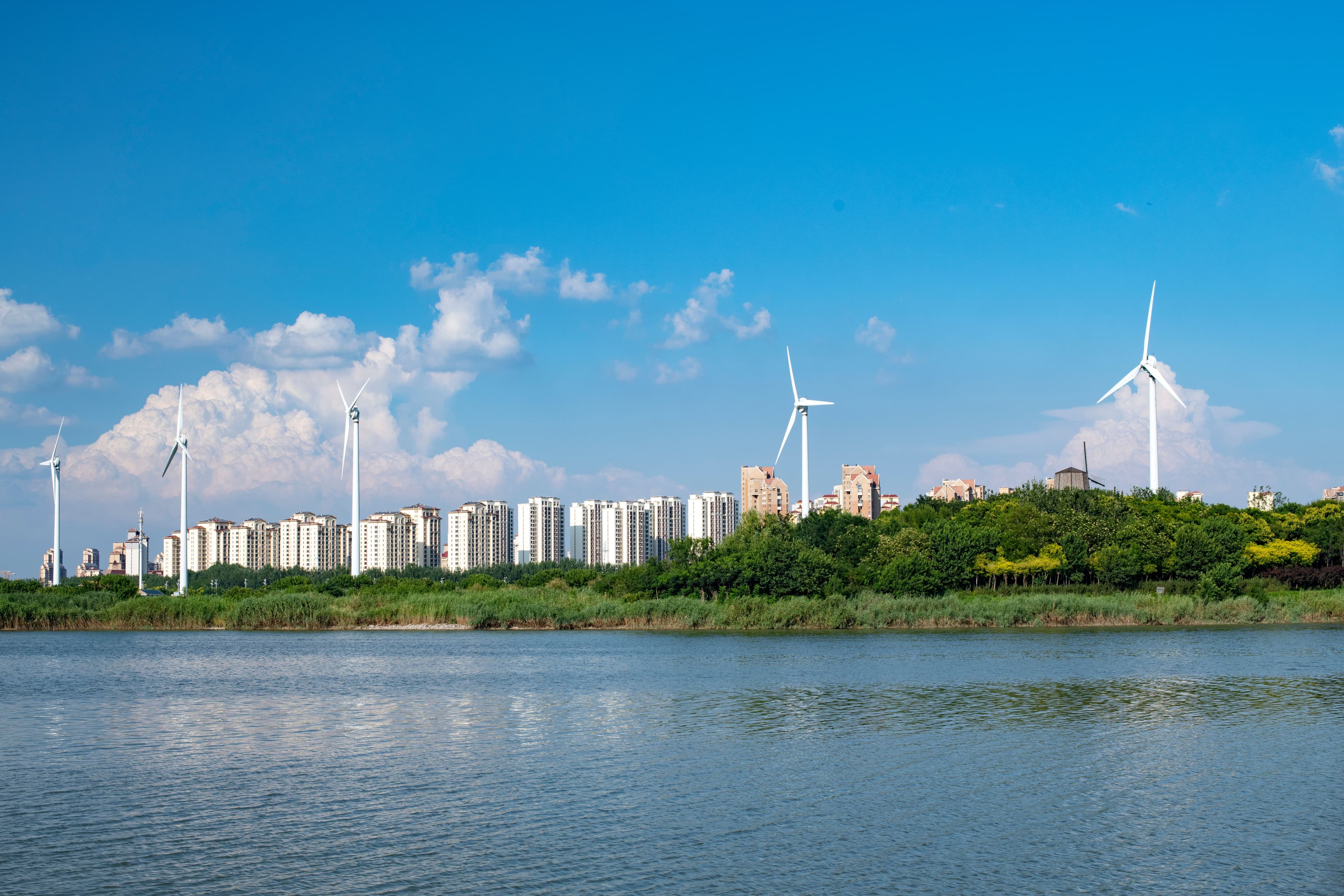 Wind turbines beside high-rise residential towers on a lakeshore